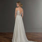 A bride is shown from the back, wearing a wedding gown with a lace bodice and a deep V-back. The gown features thin straps and a flowing chiffon skirt with a soft train. Her hair is styled in a chic low bun, adding to the gown's elegant and timeless look.