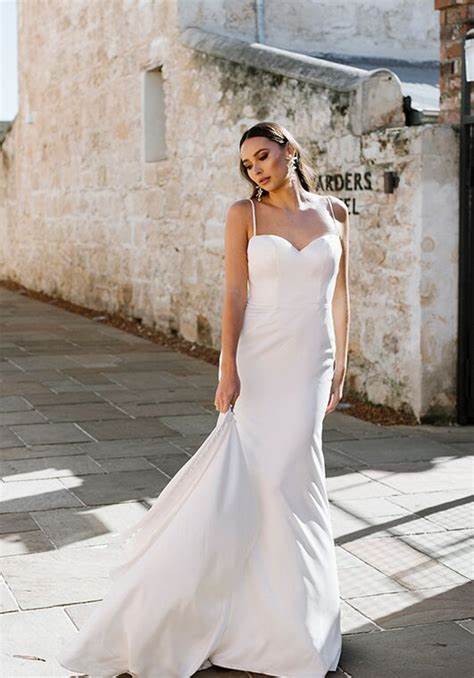 Stunning bridal gown featuring a sleek silhouette, delicate spaghetti straps, and a heart-shaped neckline, perfect for the modern bride who desires timeless elegance and effortless sophistication.