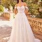 This breathtaking bridal gown features a romantic off-the-shoulder neckline with delicate lace details that create a stunning illusion bodice. The full skirt, adorned with intricate lace appliqués, flows gracefully to the floor, creating a timeless and elegant silhouette. Set against a picturesque background with lush greenery and ornate stonework, this dress is perfect for the bride who desires a blend of classic beauty and modern romance.