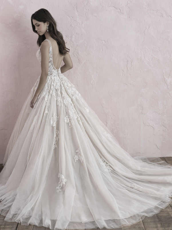 Romantic A-line wedding gown featuring a deep V-back, delicate floral lace appliqués, and a flowing tulle skirt that cascades beautifully into a train.