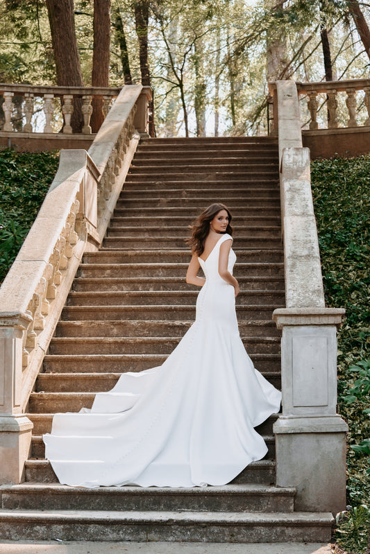 Romantic off-the-shoulder wedding gown with floral lace appliqués and a flowing tulle train. The illusion back detail adds a touch of elegance, perfect for brides seeking a soft, ethereal bridal look.