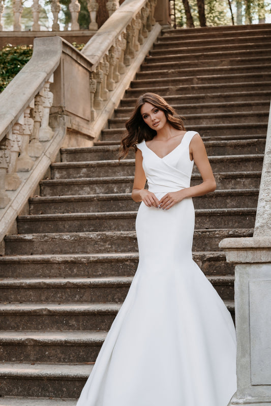 Romantic off-the-shoulder wedding gown with floral lace appliqués and a flowing tulle train. The illusion back detail adds a touch of elegance, perfect for brides seeking a soft, ethereal bridal look.