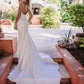 Sleek, fitted wedding gown featuring a low back and button detail down the long, flowing train. A modern, minimalist bridal look for an elegant outdoor ceremony.