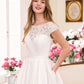 A close-up of a bride in a wedding gown with a lace bodice and cap sleeves, showcasing the delicate floral lacework and the elegant simplicity of the design. The soft pleats of the satin skirt and the bride's relaxed pose enhance the gown's timeless charm.