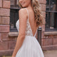 Back view of a modern wedding gown featuring a plunging lace bodice, thin straps, and a flowing skirt, perfect for the bride seeking an elegant and contemporary bridal look.